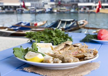 Yeşiller ve limon mavi ahşap tablo açık havada, deniz ürünleri ile kızarmış balık yakın çekim