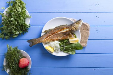 Yeşiller ve limon ile ızgara levrek balık üstten görünüm mavi ahşap tablo