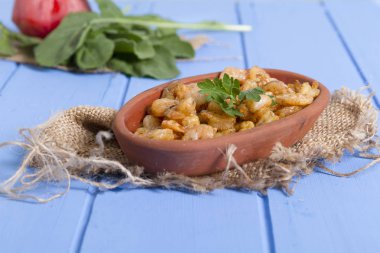 Lezzetli küçük kırmızı karides tereyağı ile baharat baharat haşlanmış. Geleneksel Yunan çanak çömlek içinde hizmet veren karides güveç. Üstten görünüm mavi rustik arka plan. En ortak gıda alerjenleri arasında diğer kabuklu deniz ürünleri.