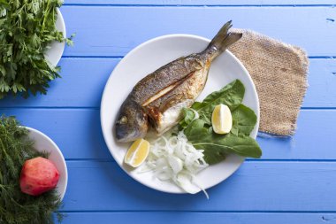 Yeşiller ve limon ile ızgara dorado balık üstten görünüm mavi ahşap masa, deniz ürünleri kavramı üzerinde