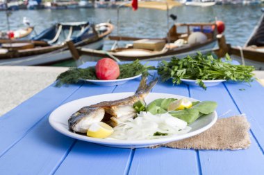 Yeşil ve mavi ahşap masa açık havada limon ile ızgara dorado balık
