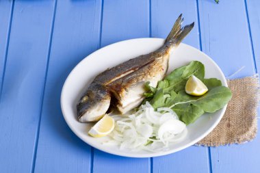 Yeşil ve mavi ahşap masa, deniz ürünleri kavramı üzerinde limon ile ızgara dorado balık