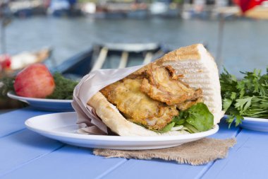 Mavi ahşap masada açık havada lezzetli kızarmış balık sandviç