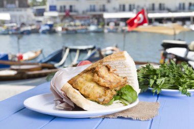 Mavi ahşap masada açık havada lezzetli kızarmış balık sandviç