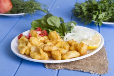 Kızarmış balık dilimleri ile yeşil ve mavi ahşap masa, deniz ürünleri üzerinde limon