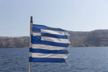 Santorini Adası karşı deniz arka plan ile sallayarak Yunan bayrağı. Gökyüzü mavi beyaz resmen üzerinde dokuz eşit yatay şeritler dayalı ulusal sembolleri biri olarak Yunanistan tarafından tanınan. Kopya alanı.