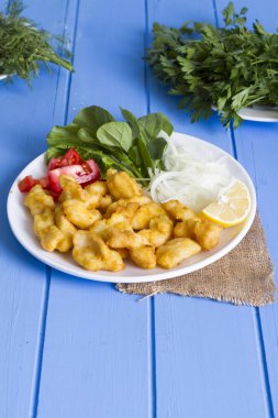 Kızarmış balık dilimleri yeşil ve mavi ahşap masa, deniz ürünleri üzerinde limon ile yakın çekim