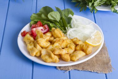 Kızarmış balık dilimleri ile yeşil ve mavi ahşap masa, deniz ürünleri üzerinde limon