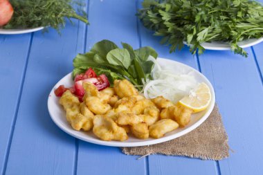 Kızarmış balık dilimleri ile yeşil ve mavi ahşap masa, deniz ürünleri üzerinde limon