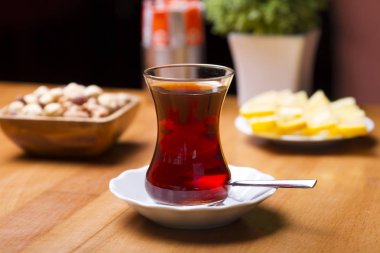 Türkçe ve Arapça geleneksel ramazan siyah çay beyaz tabak, metal kaşık, limon dilimi, kurabiye, bisküvi ve ahşap masa arka plan üzerinde fındık ile özel tasarım cam