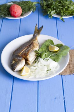 Yeşil ve mavi ahşap masa, deniz ürünleri kavramı üzerinde limon ile ızgara dorado balık