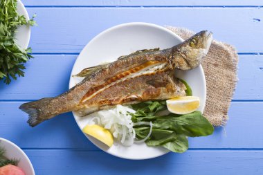 Yeşiller ve limon ile ızgara levrek balık üstten görünüm mavi ahşap tablo