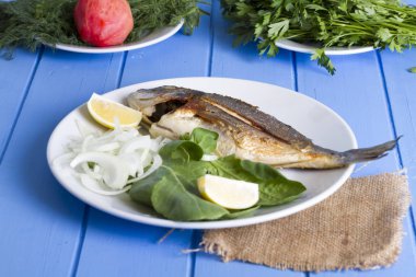 Yeşil ve mavi ahşap masa, deniz ürünleri kavramı üzerinde limon ile ızgara dorado balık