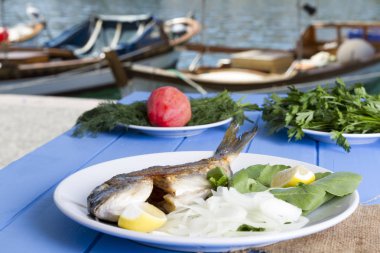 Yeşil ve mavi ahşap masa açık havada limon ile ızgara dorado balık