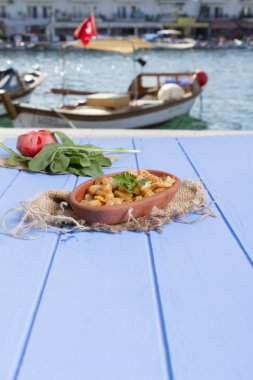 Lezzetli küçük kırmızı karides tereyağı ile baharat baharat haşlanmış. Geleneksel Yunan çanak çömlek içinde hizmet veren karides güveç. Üstten görünüm mavi rustik arka plan. En ortak gıda alerjenleri arasında diğer kabuklu deniz ürünleri.