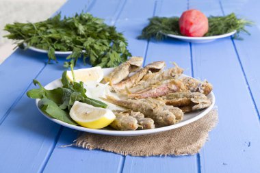 Yeşil ve mavi ahşap masa, deniz ürünleri üzerinde limon ile kızarmış balık