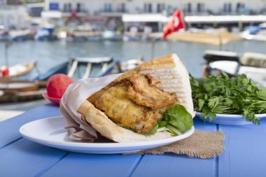 Mavi ahşap masada açık havada lezzetli kızarmış balık sandviç