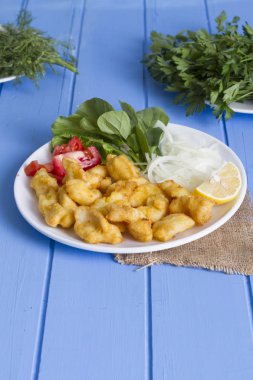 Kızarmış balık dilimleri yeşil ve mavi ahşap masa, deniz ürünleri üzerinde limon ile yakın çekim