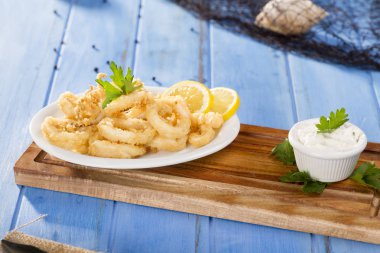 Zeytinyağı ile beyaz tabak lezzetli deniz ürünleri altın kızarmış gevrek kalamar halkaları 