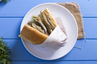 Türk geleneksel Delicious derin kurutulmuş Avrupa Hamsili balık malzemeleri yuvarlak tabak, mavi rustik arka plan masaya dilimlenmiş domates, roka salatası, beyaz soğan ve limon hizmet sandviç. Kopya alanı