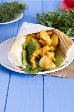 kızarmış balık dilimleri ve mavi ahşap masa üzerinde yeşillik ile lezzetli sandviç yakın çekim 