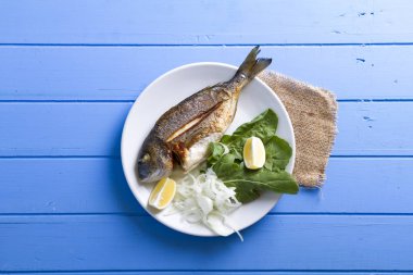 Yeşiller ve limon ile ızgara dorado balık üstten görünüm mavi ahşap masa, deniz ürünleri kavramı üzerinde