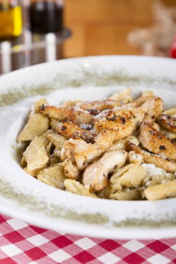 Lezzetli dilimlenmiş ızgara tavuk, domates, parmesan peyniri ve kremsi otlu soslu penne makarna ile cola ve domates ahşap masa arka plan üzerinde beyaz kase yemek hizmet üzerinde.