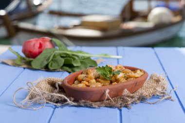 Lezzetli küçük kırmızı karides tereyağı ile baharat baharat haşlanmış. Geleneksel Yunan çanak çömlek içinde hizmet veren karides güveç. Üstten görünüm mavi rustik arka plan. En ortak gıda alerjenleri arasında diğer kabuklu deniz ürünleri.