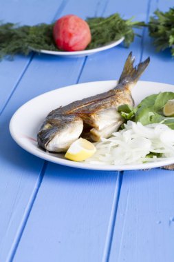 Yeşil ve mavi ahşap masa, deniz ürünleri kavramı üzerinde limon ile ızgara dorado balık