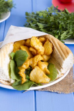 kızarmış balık dilimleri ve mavi ahşap masa üzerinde yeşillik ile lezzetli sandviç yakın çekim 