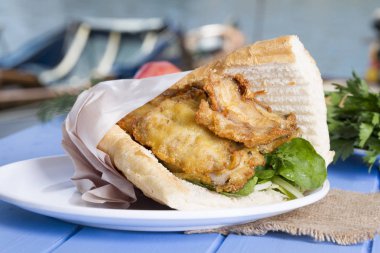 lezzetli kızarmış balık sandviç üzerinde mavi ahşap masa üzerinde Kapat 