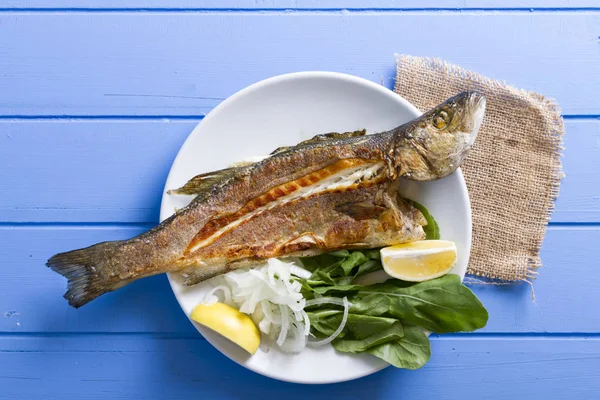 Yeşiller ve limon ile ızgara levrek balık üstten görünüm mavi ahşap tablo