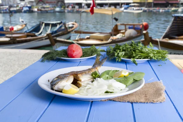 Yeşil ve mavi ahşap masa açık havada limon ile ızgara dorado balık