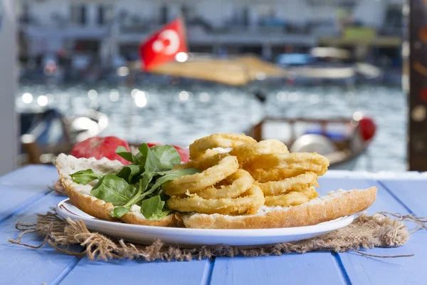 Lezzetli altın Ev yapımı Deep Fried tuzlu beyaz hizmet patates kızartması plaka rustik mavi ahşap masa arka plan üzerinde yuvarlak. Parmağı cipsi veya patates batonnet veya allumette derin kızarmış patates kesmek.