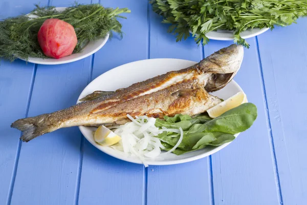Yeşil ve mavi ahşap masa, deniz ürünleri kavramı üzerinde limon ile ızgara levrek balık