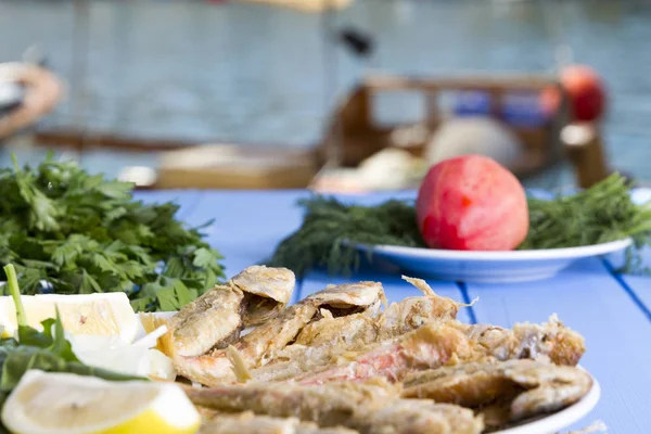 Yeşiller ve limon mavi ahşap tablo açık havada, deniz ürünleri ile kızarmış balık yakın çekim
