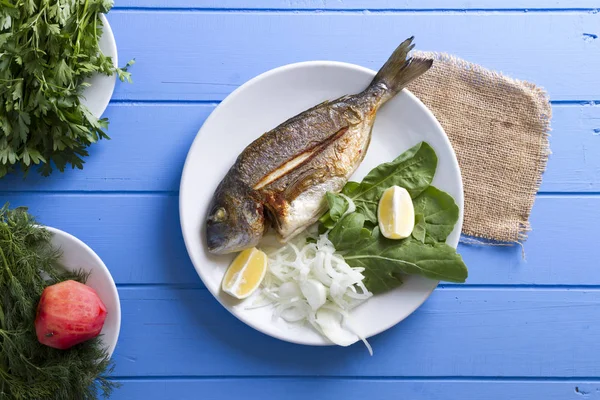 Yeşiller ve limon ile ızgara dorado balık üstten görünüm mavi ahşap masa, deniz ürünleri kavramı üzerinde