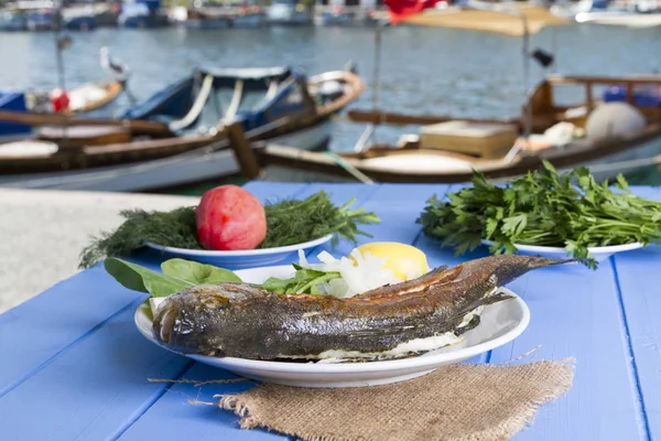 Yeşil ve mavi ahşap masa açık havada limon ile ızgara levrek balık