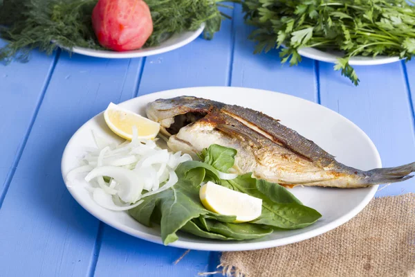 Yeşil ve mavi ahşap masa, deniz ürünleri kavramı üzerinde limon ile ızgara dorado balık