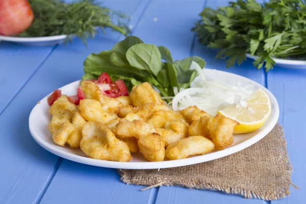 Kızarmış balık dilimleri ile yeşil ve mavi ahşap masa, deniz ürünleri üzerinde limon