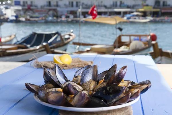 Türk lezzetli pirinç dolması domates ile hizmet veren midye, yeşil roka salatası ve sulu limon rustik mavi ahşap arka plan masa. Metin alanı için alan kopyalayın. Midye Dolma.