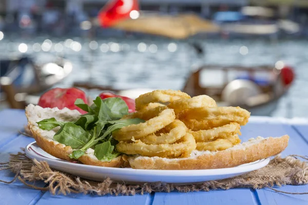 Lezzetli altın Ev yapımı Deep Fried tuzlu beyaz hizmet patates kızartması plaka rustik mavi ahşap masa arka plan üzerinde yuvarlak. Parmağı cipsi veya patates batonnet veya allumette derin kızarmış patates kesmek.