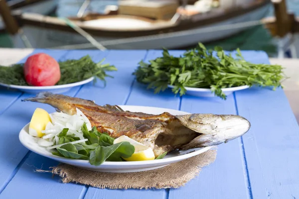 Yeşil ve mavi ahşap masa açık havada limon ile ızgara levrek balık