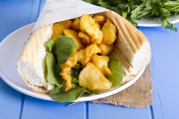 kızarmış balık dilimleri ve mavi ahşap masa üzerinde yeşillik ile lezzetli sandviç yakın çekim 