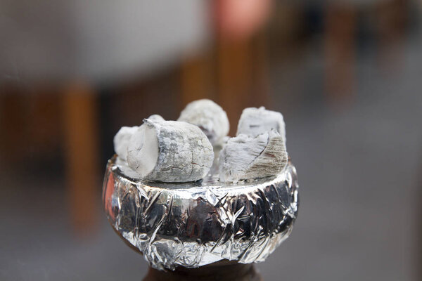 Close up Shisha hookah with  hot coals. Sparks from breathe. Modern hookah with coconut charcoal for relax and shisha smoke. Blurred background. Copy Space.