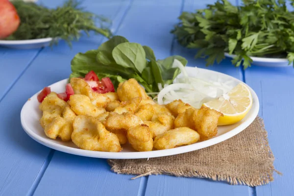 Kızarmış balık dilimleri ile yeşil ve mavi ahşap masa, deniz ürünleri üzerinde limon