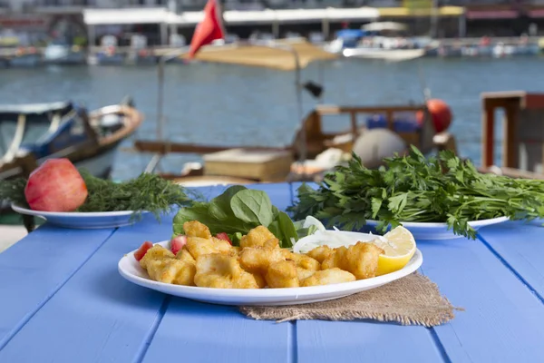 Kızarmış balık dilimleri ile yeşil ve mavi ahşap masa açık havada limon