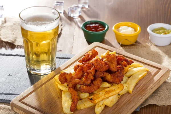 Soğuk köpüklü altın soğutulmuş taslak bira hizmet plakalı lezzetli sıcak gevrek ev yapımı taze kızarmış tavuk kanatları, dilimlenmiş domuz sosisi ve kişiler üzerine ahşap bambu tahta baharatlı sos ile.