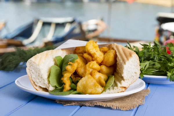 kızarmış balık dilimleri ve mavi ahşap masa üzerinde yeşillik ile lezzetli sandviç yakın çekim 