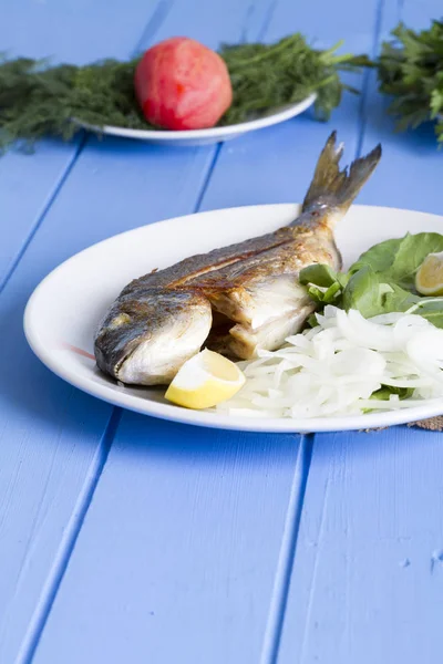 Yeşil ve mavi ahşap masa, deniz ürünleri kavramı üzerinde limon ile ızgara dorado balık